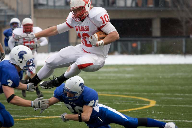 a football player in mid air while another player is falling