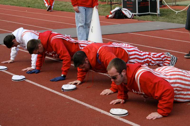 a group of men in red tracksuits doing push ups on a track