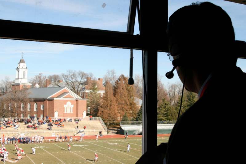 a man looking out a window at a football game