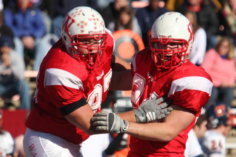 two football players wearing helmets and holding hands