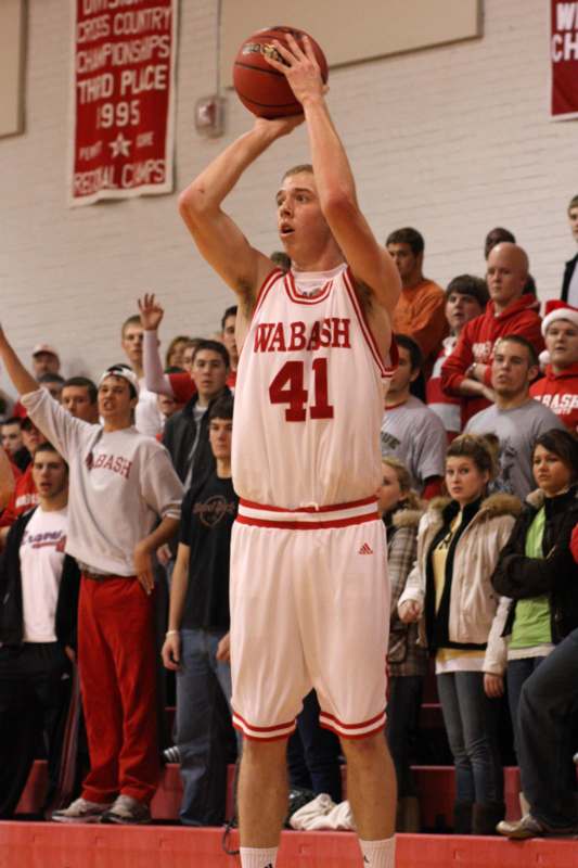 a basketball player in a white uniform with a red number on the front and a crowd of people watching