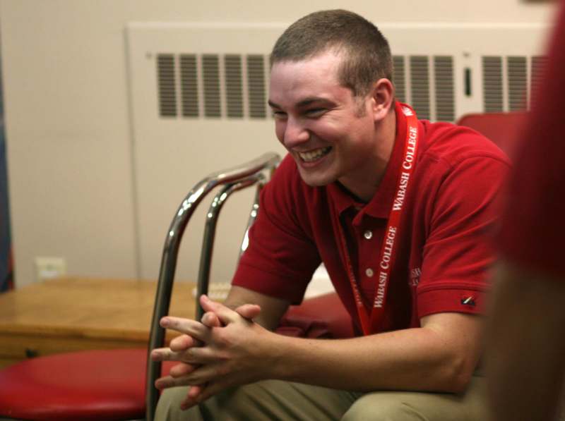 a man laughing while sitting in a chair