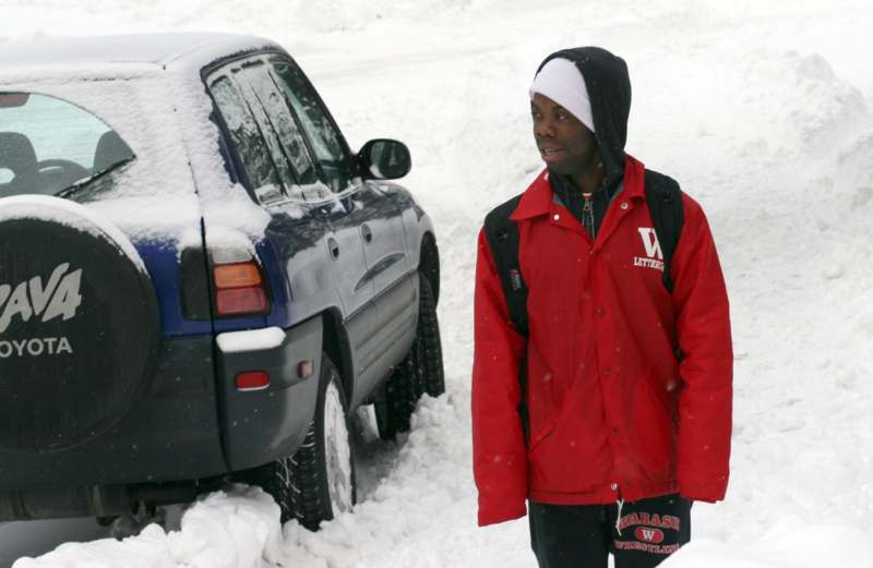 a man standing in the snow next to a car