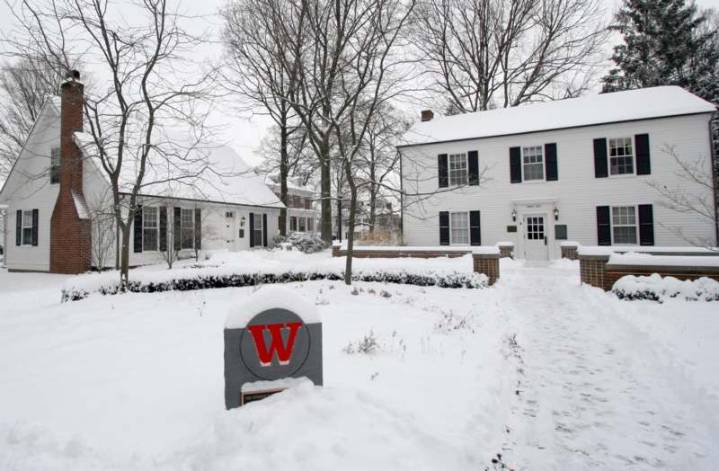 a snow covered yard with a sign in front of a house