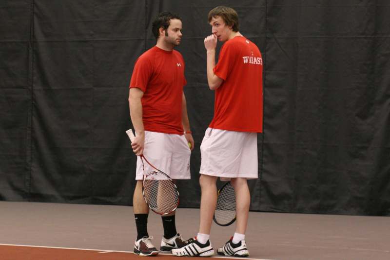 two men in red shirts holding tennis rackets