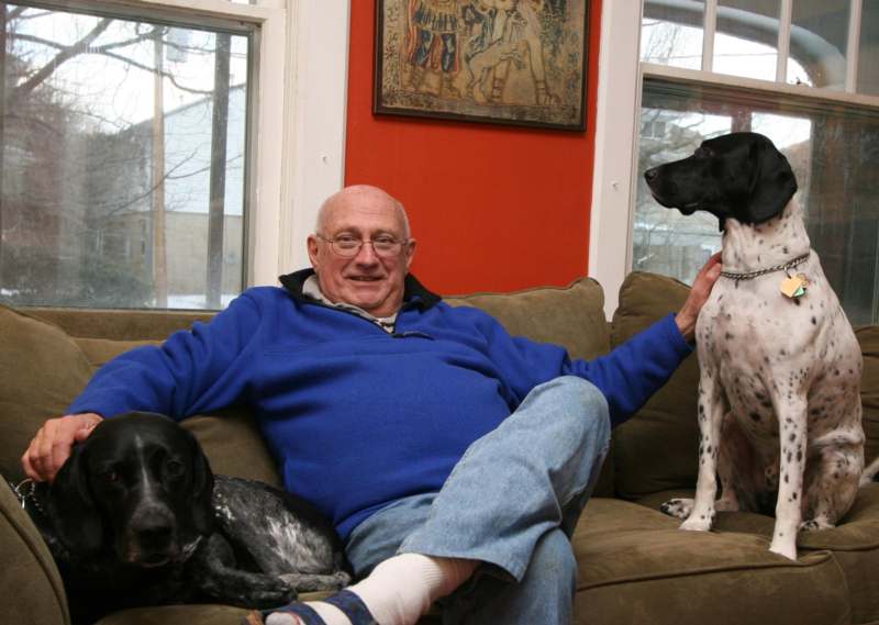 a man sitting on a couch with two dogs