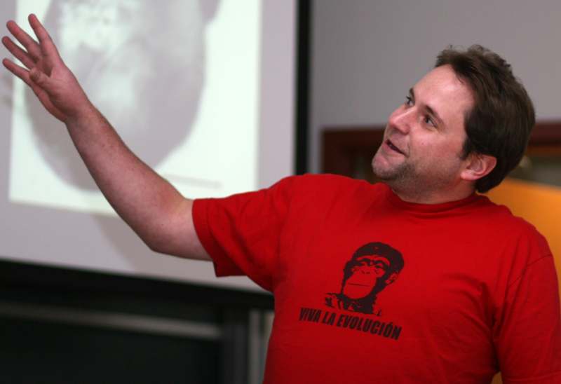 a man in a red shirt pointing at a screen