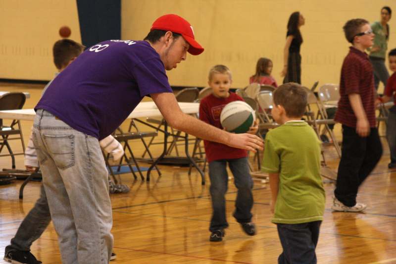 a man holding a ball with a boy in a gym