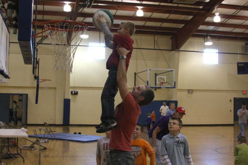 a man holding a boy up to a basketball
