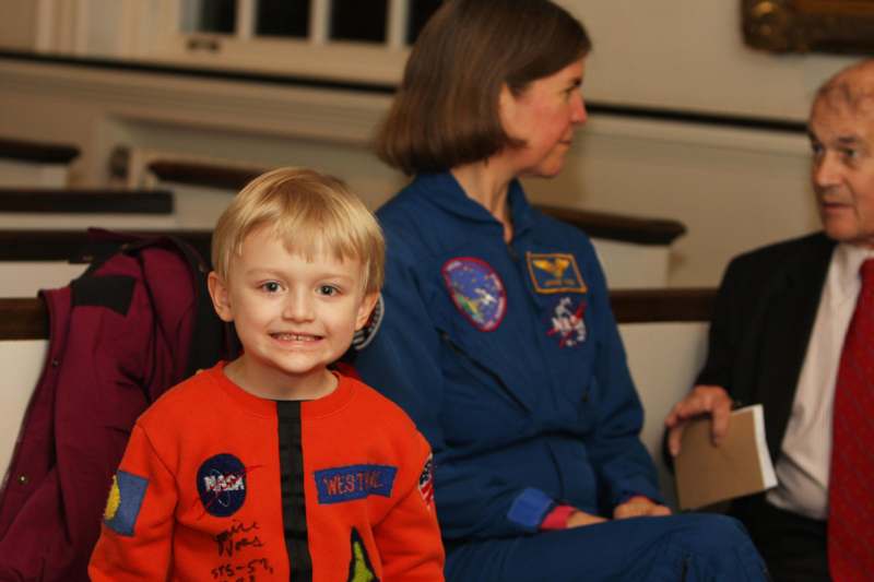 a boy in an orange space suit with patches on it