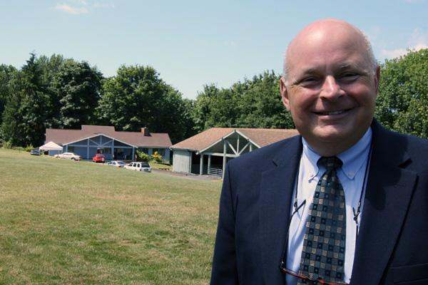 a man in a suit and tie standing in front of a house