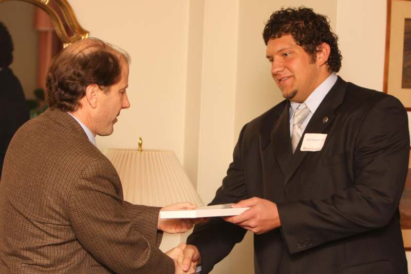a man in suit handing a book to another man