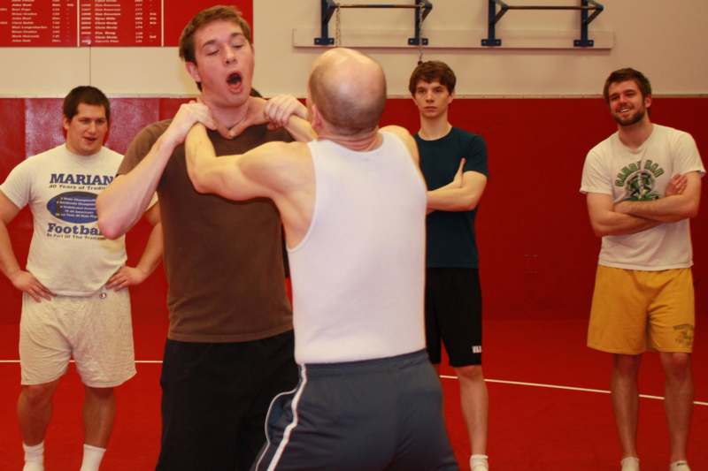 a man in a white tank top punching a man in a gym
