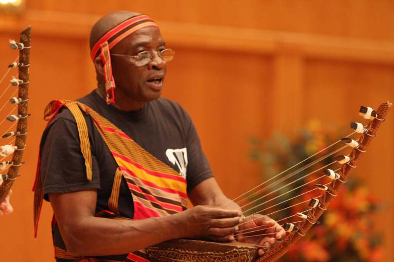 a man wearing glasses and a headband playing a string instrument