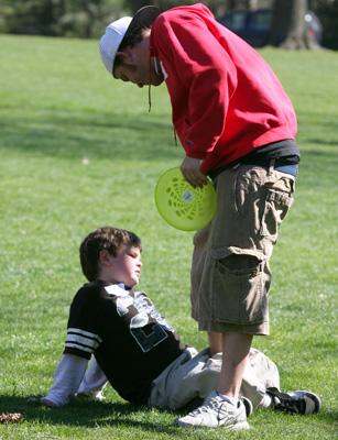 a man holding a frisbee next to a boy lying on the ground