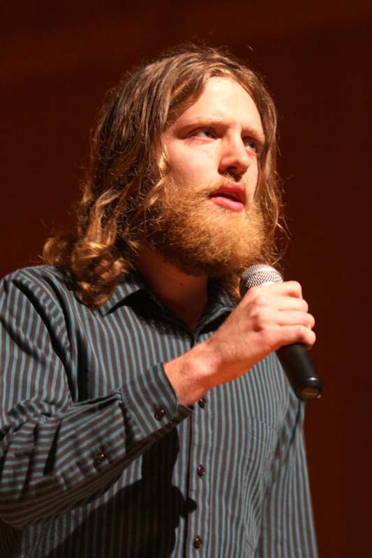 a man with long hair and a beard holding a microphone