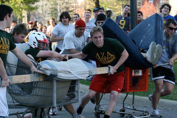 a group of people pushing a bed in shopping carts