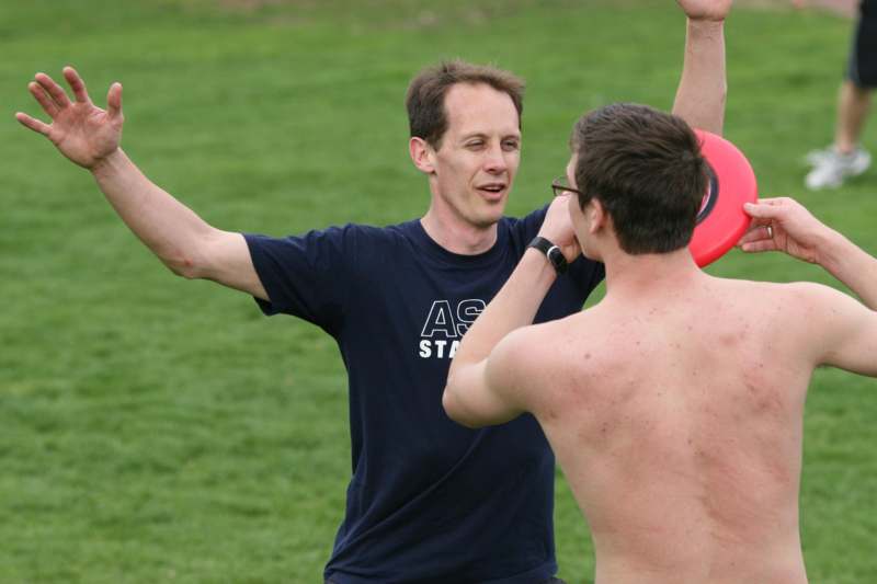 a man holding a frisbee with another man in the background