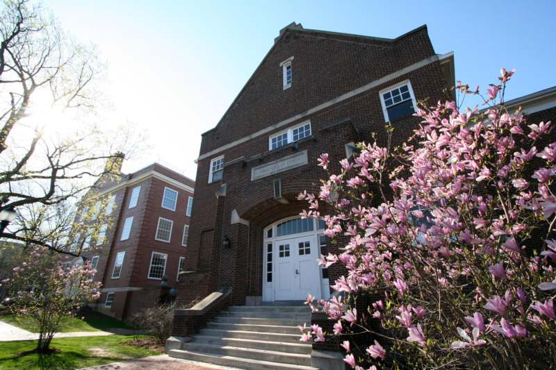 a brick building with a white door and pink flowers