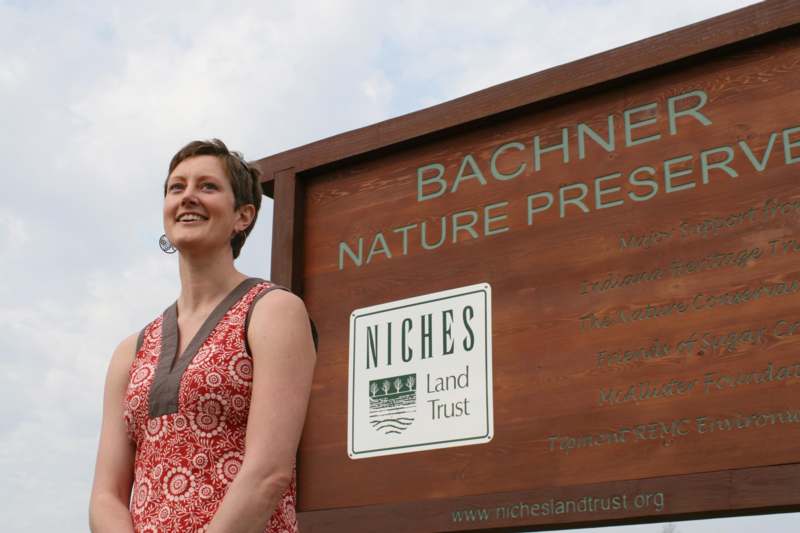 a woman standing next to a sign