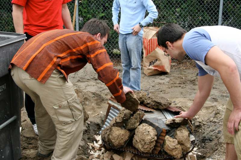 a group of men putting rocks on a grill