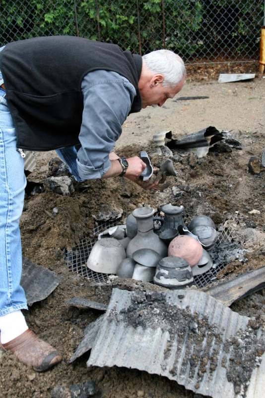a man kneeling next to a pile of broken pots