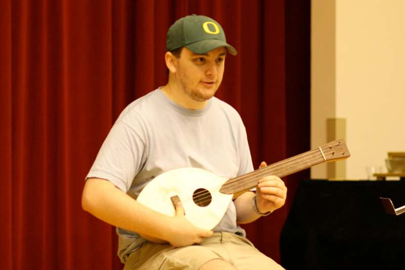 a man in a green hat playing a mandolin