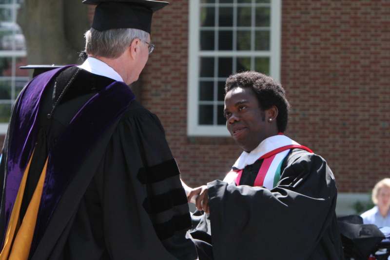 a man in a graduation gown talking to a man