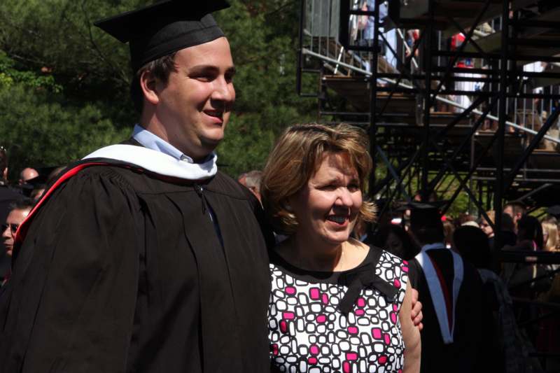 a man in a graduation gown and cap standing next to a woman