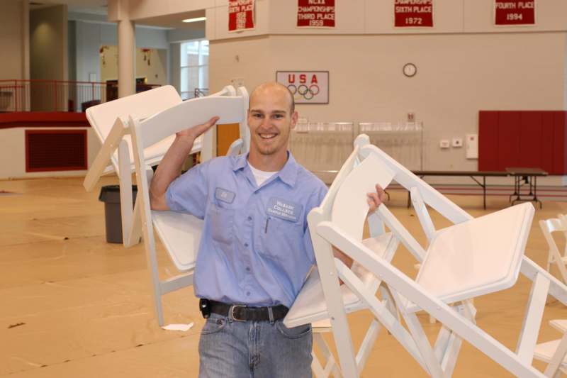 a man holding a stack of chairs