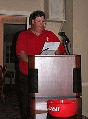 a man standing at a podium reading a paper