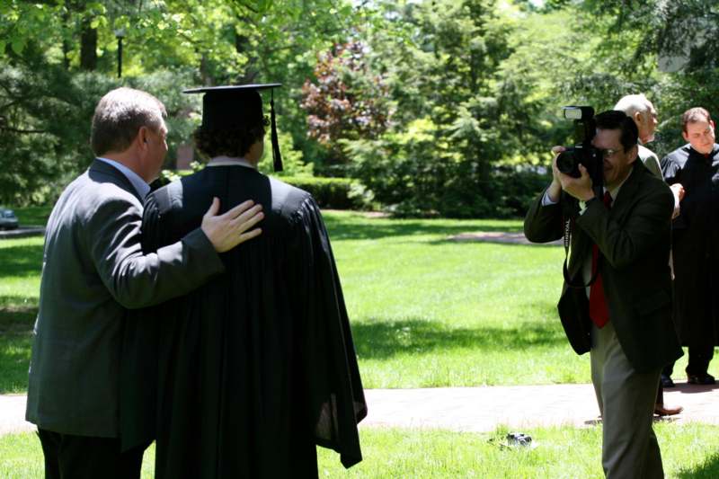 a man taking a picture of a man in a graduation gown