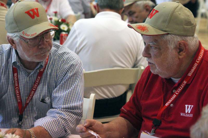 men wearing hats and lanyards sitting at a table