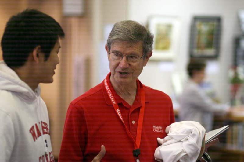 a man in a red shirt talking to a young man