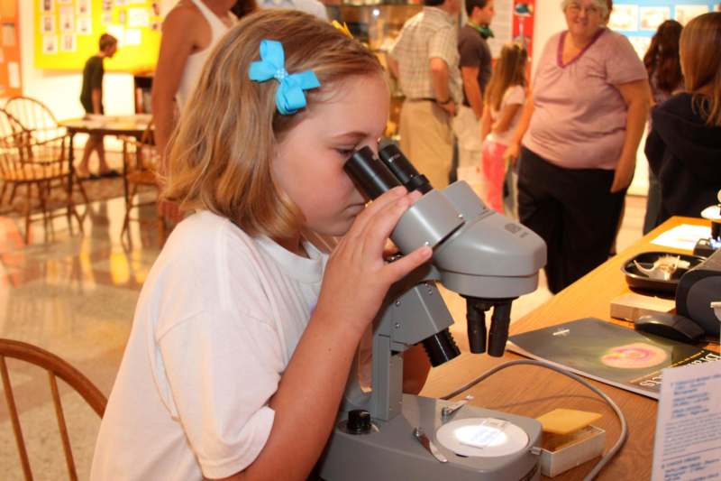 a girl looking through a microscope