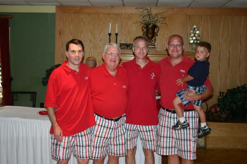 a group of men in red shirts and plaid shorts