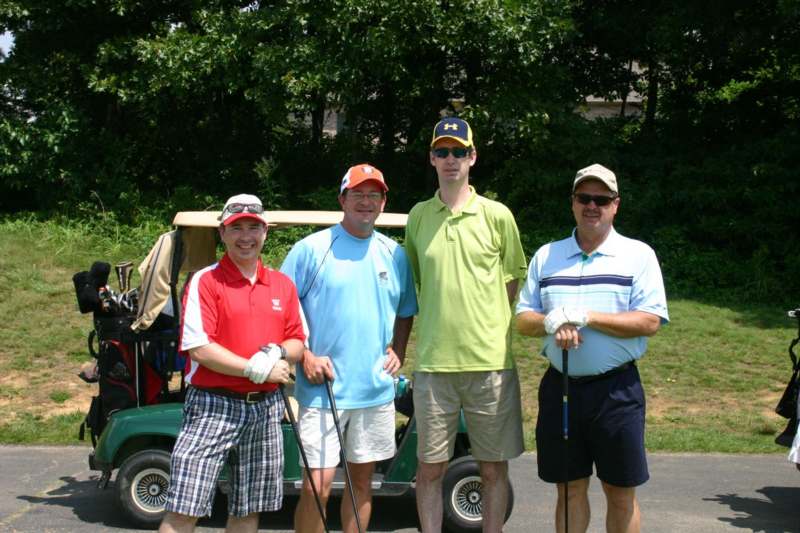 a group of men standing in front of a golf cart