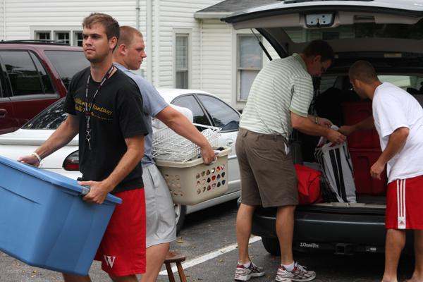a group of men loading clothes into a car