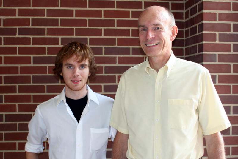 a man and boy standing in front of a brick wall
