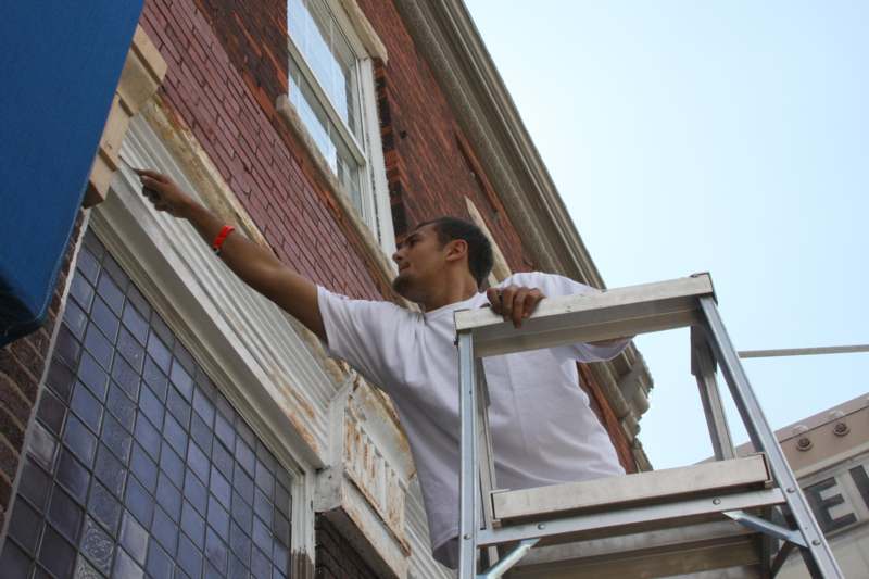 a man on a ladder painting a building