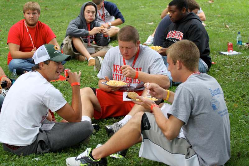 a group of people sitting on the grass eating food