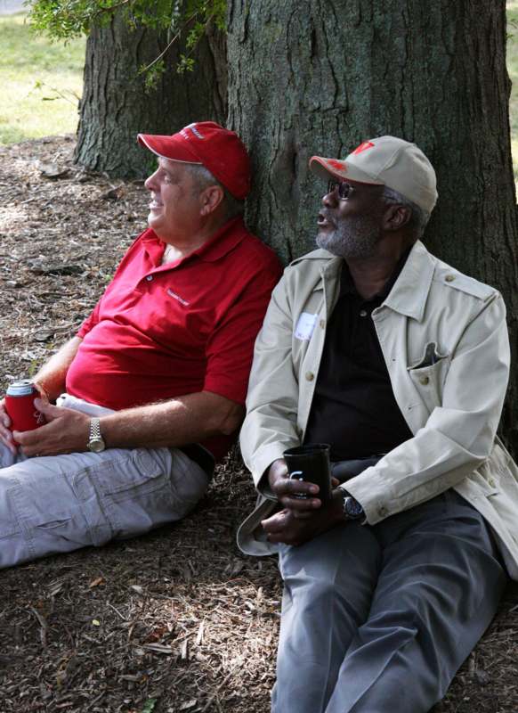 two men sitting next to a tree