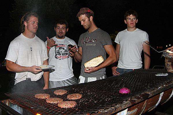 a group of men standing around a grill