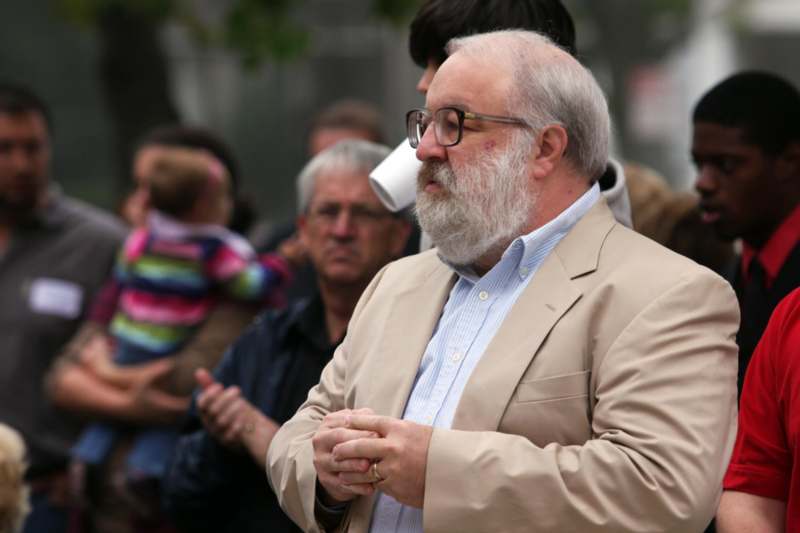 a man with a beard and glasses standing in front of a crowd