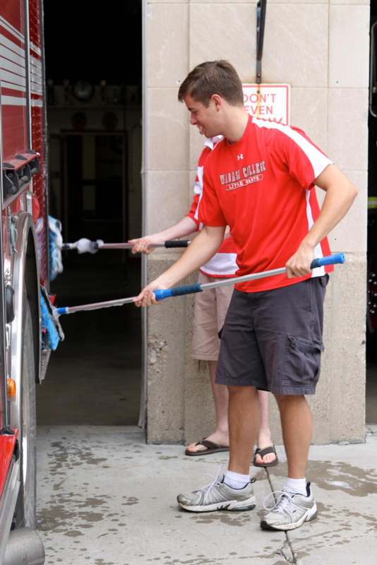 a man holding a broom and cleaning a fire truck
