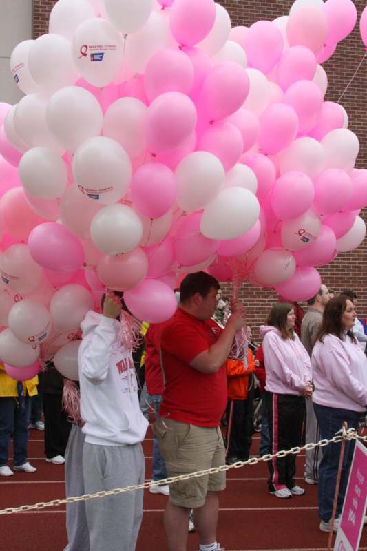 a man holding a bunch of pink and white balloons