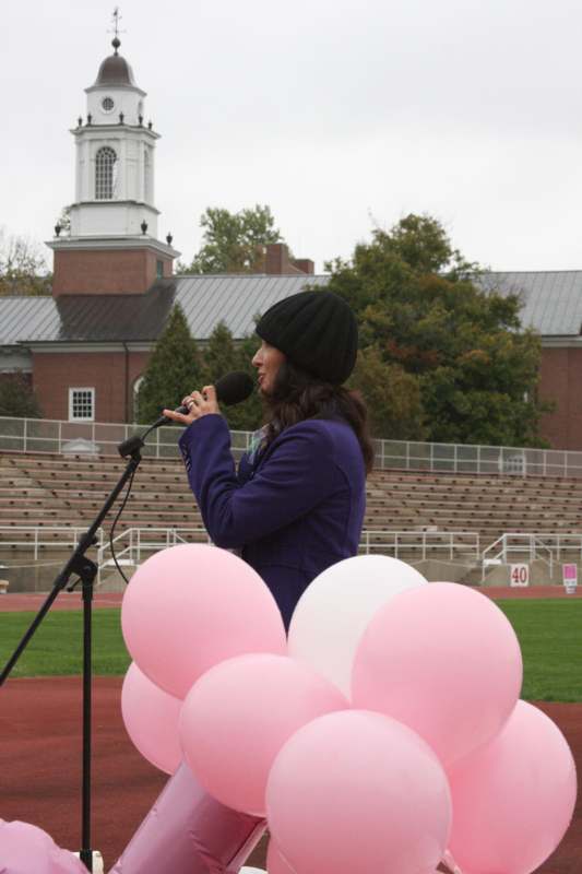 a woman speaking into a microphone with pink balloons