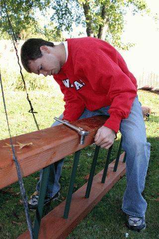 a man in a red sweatshirt working on a wood beam
