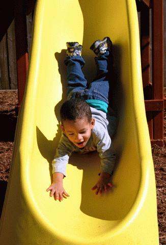 a child sliding down a yellow slide