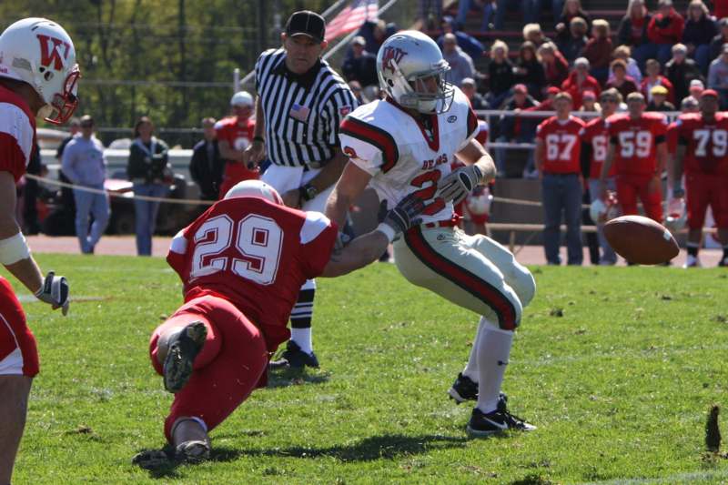 a football player in a red uniform kicking another football player